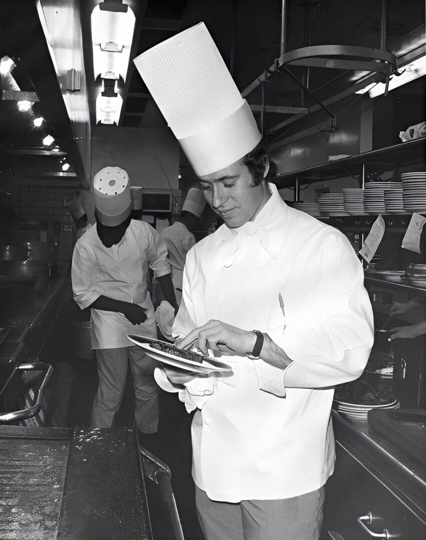 Chef plating food in a busy kitchen.